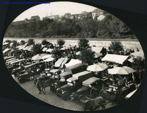 Marché alimentaire, rue de la Gare. Vue prise en hauteur des voitures et stands des marchands le long de ce qui est aujourd'hui la rue Leclerc. [cote 4Fi280]